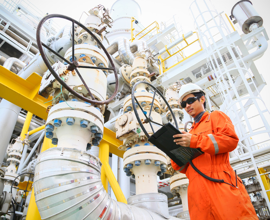 Industrial safety worker outside observing data next to large machinery