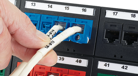 labeled patch panel with terminated cable and hand turning 