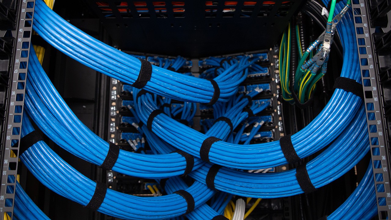 cat6a-blog-b-1280x720 Bundles of blue copper cables routed into the back of a telecommunications rack