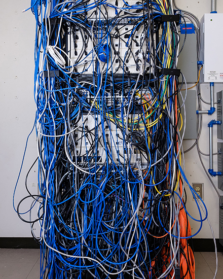 Another cable management rack with hundreds of cables tangled into a mess, exhibiting network mismanagement prior to Panduit provisions