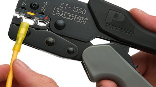A close-up of a hand holding a tool wire terminating