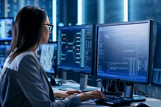 Woman working at a computer with multiple monitors in front of her